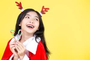 A girl with braces holding 2 candies